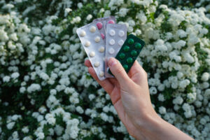 a hand holding pills in front of white flowers