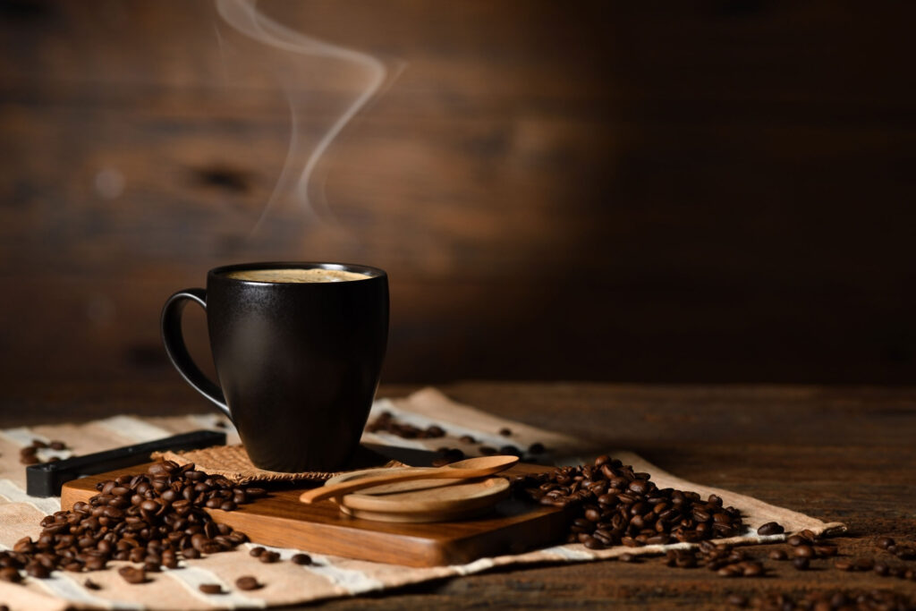 a cup of coffee with steam on top of coffee beans