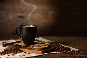 a cup of coffee with steam on top of coffee beans