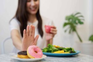 una mujer con un donut en la mano y un plato de comida