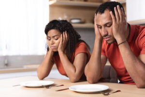 a man and woman sitting at a table with plates and utensils