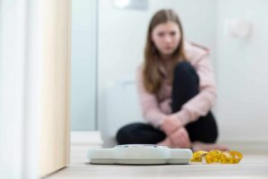 a woman sitting on the floor with a scale