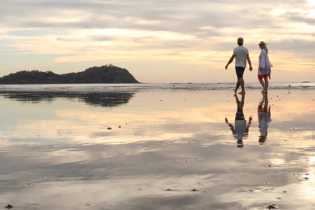 un par de personas paseando por una playa