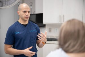 El doctor McGowan, un médico calvo con bata azul, hablando con una mujer