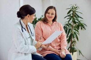 a woman sitting in a chair with a doctor holding a paper